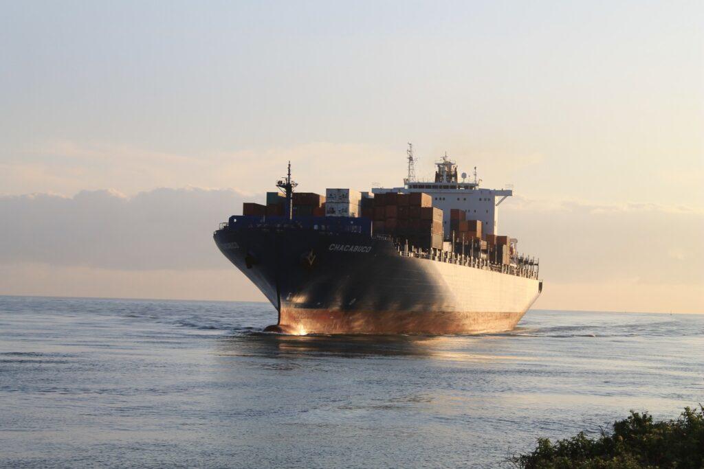 Photograph of a container ship near shore approaching a canal to enter port. Marine Surveyor Houston